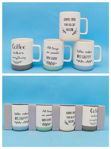 White ceramic mugs with black coffee-themed lettering, leafy details and contrasting coloured bases
