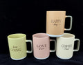 Pastel ceramic mugs with decorative lettering, contrasting squared handles and pale bases